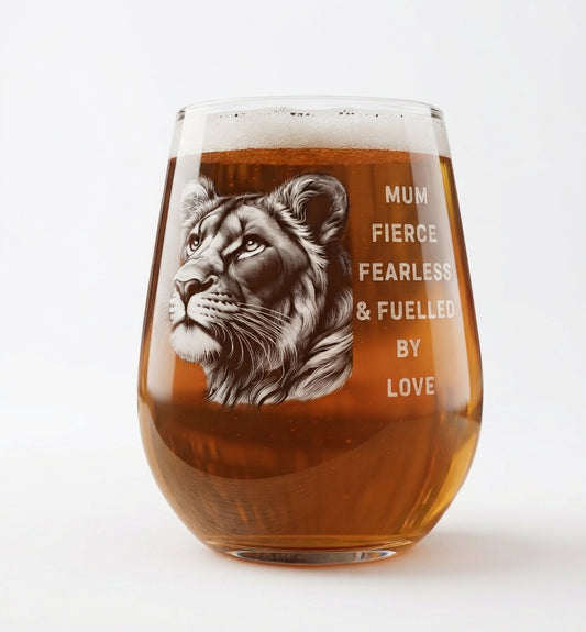 A stemless wine glass filled with amber beer, featuring a detailed engraving of a lion's head and the text 'MUM FIERCE FEARLESS & FUELLED BY LOVE' on a clean white background.