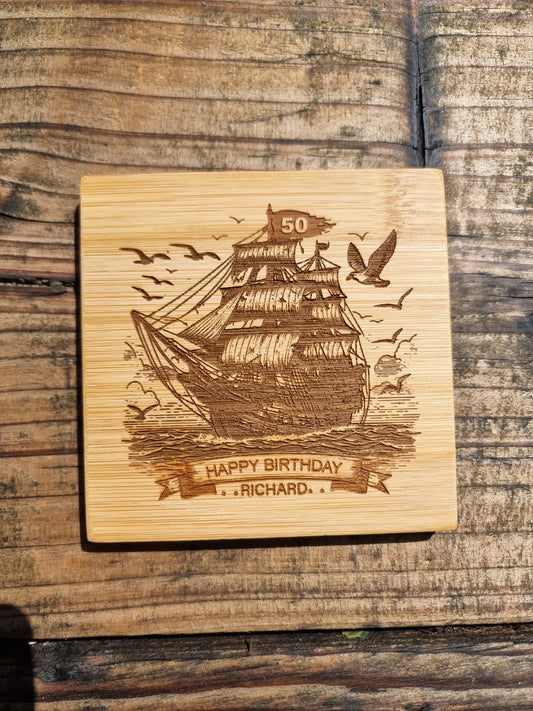 Personalised rum glass with ship design, custom name and age, shown with optional bamboo coaster and varnished wooden gift box – nautical themed gift for him