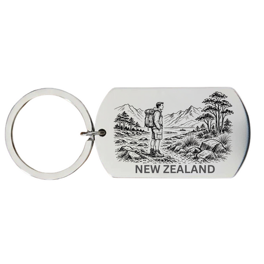 New Zealand backpacker keyring laser engraved stainless steel dog tag with male backpacker native silver fern fronds and mountain landscape on white background