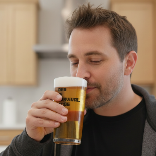 Personalised pint beer glass with “Dad in Survival Mode” printed in a blocky pixel-style gaming font inspired by Minecraft, clear glass with bold black text, novelty gift for gamer dads, Father’s Day or birthday present.