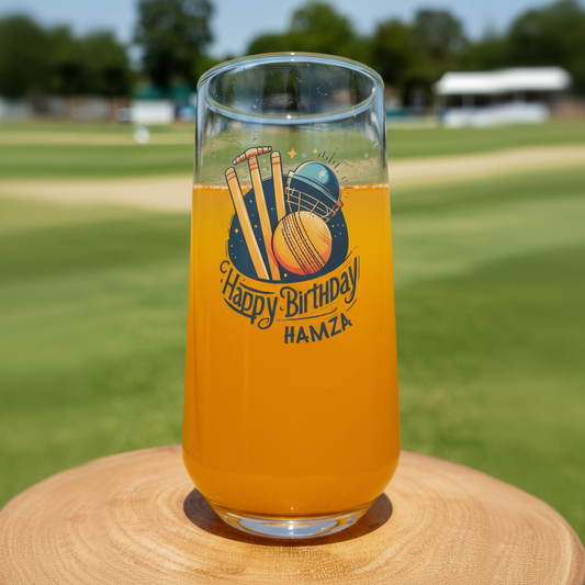 Personalised cricket birthday glass with custom name, featuring stumps, helmet and ball design, on cricket ground background