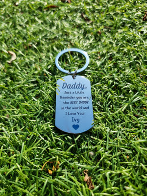 Best Daddy in the World personalised stainless steel dog tag keyring engraved with sentimental message and child's name Alfie with heart, photographed in grass, emotional Father's Day gift from child