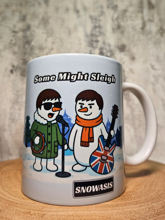 White ceramic mug with cartoon snowmen holding musical instruments and the text “Some Might Sleigh”.