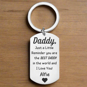Best Daddy in the World personalised stainless steel dog tag keyring engraved with sentimental message and child's name Alfie with heart, photographed on wooden background, emotional Father's Day gift from child