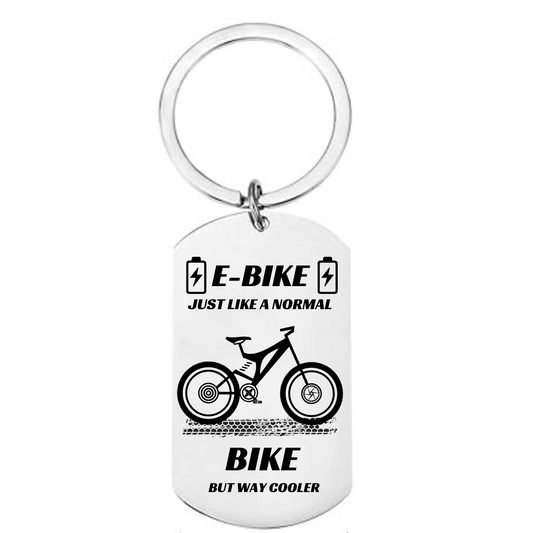 "Funny e-bike keychain with metal dog tag design, battery icons, mountain e-bike graphic and text reading just like a normal bike but way cooler"