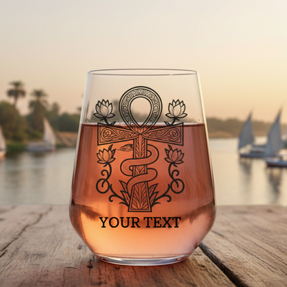 Personalised wine glass featuring a detailed Ankh symbol with a coiled serpent around the shaft and four lotus flowers, ornate scrollwork border, with space for custom text at the base
