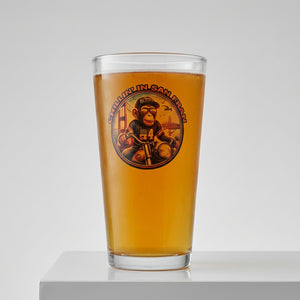 A glass of beer with a logo that includes a monkey riding a motorcycle across the Golden Gate Bridge.