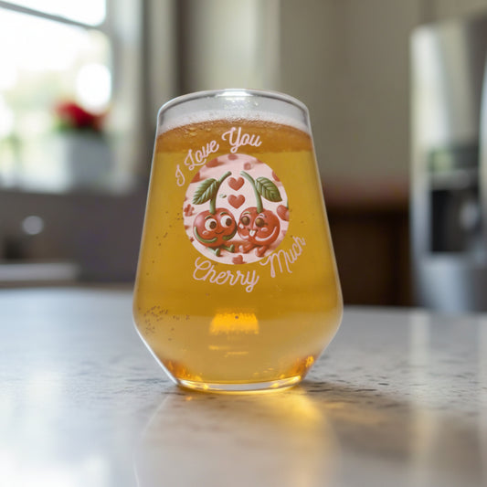 A glass with a 'I Love You Cherry Much' design, featuring an illustration of two cherries and text on the side, filled with a beverage, placed on a surface with red rose petals scattered around.