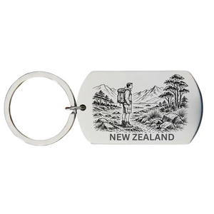 New Zealand backpacker keyring laser engraved stainless steel dog tag with male backpacker native silver fern fronds and mountain landscape on white background