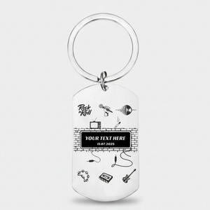 A silver metal dog tag keychain with a circular split ring, featuring black printed graphics of music instruments, a brick wall, and customizable text on a light gray background.