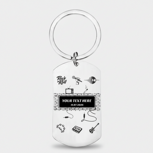 A silver metal dog tag keychain with a circular split ring, featuring black printed graphics of music instruments, a brick wall, and customizable text on a light gray background.