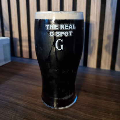 Real G Spot pint glass filled with dark Irish stout beer on a wooden bar