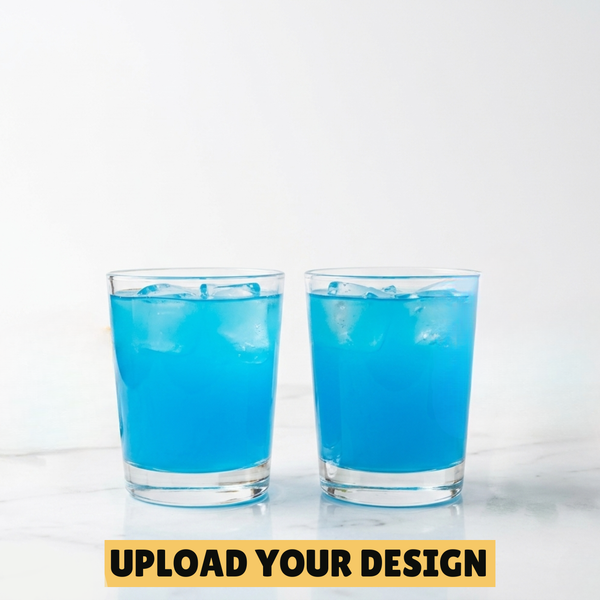 Two personalised 25ml shot glasses filled with blue cocktail on marble surface, unique custom printed party gift
