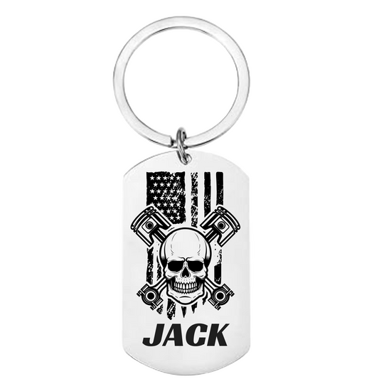 Skull and crossbones dog tag keychain with pistons, American flag background, custom name on front, engraved message on back