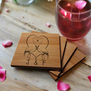 Personalised bamboo or slate coaster featuring two flamingos forming a heart shape with their necks, engraved with custom initials underneath, natural wood or stone texture, perfect romantic gift for couples, weddings, anniversaries, or Valentine’s Day.