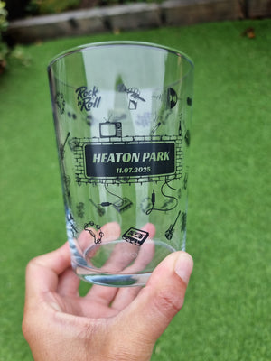 Hand holding a glass with 'Heaton Park' branding against a green background