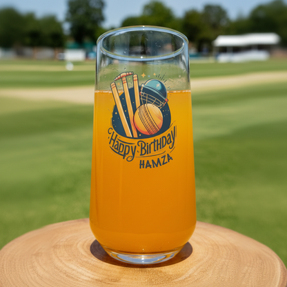 Personalised cricket birthday glass with custom name, featuring stumps, helmet and ball design, on cricket ground background