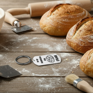 Baked bread loaves on a wooden surface with baking tools and a keychain.