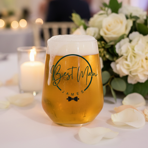Personalised best man stemless beer glass custom printed with 
bow tie design and name James on a wedding reception table