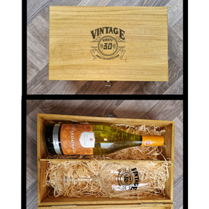 A personalised wine glass with a vintage design, presented in a wooden box alongside a bottle of wine. The glass has 'AGED TO PERFECTION' printed on it, along with a name and age.